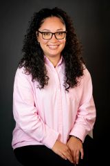 Headshot of Ashley Jimenez. She is seated wearing a pink button down shirt with her hand resting in her lap.
